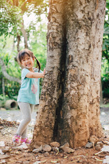 Little girl playing under the big tree. Concept for nature, global warming and Earth Day to encourage people about the environmental protection.