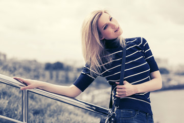 Young fashion woman in striped turtleneck t-shirt leaning on railing