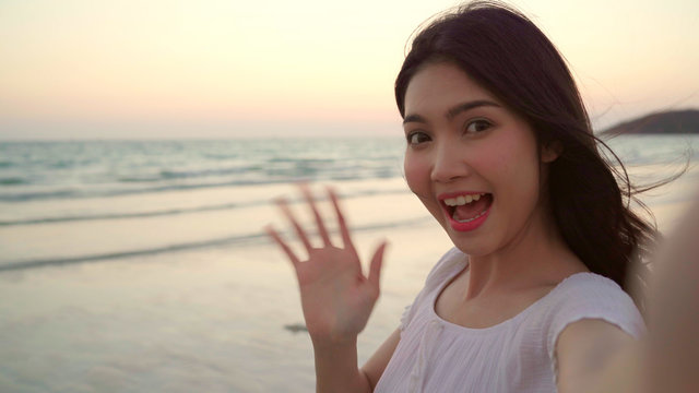Blogger Asian woman record vlog video on beach, young beautiful female happy using mobile phone make vlog video on beach near sea when sunset in evening. Lifestyle women travel on beach concept.