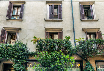 Fototapeta na wymiar Facade of an Italian house with wooden shutters on the windows and plants on the balconies
