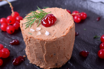Foie gras garnished with berry sauce and sea salt on the black plate