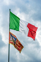 Close up view of the flag of Italy fluttering in the wind on the blue summer sky background