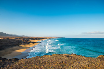Beautiful wild beach with blue ocean waves and sky - tourism summer vacation scenic place - blue sky and water - cliff point of view and scenery coastline and shore