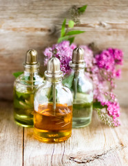 Spa perfume essential aroma oil glass bottles with flower blossoms on old wooden background