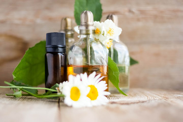 Spa perfume essence aroma oil glass bottles with flower blossoms on old wooden background