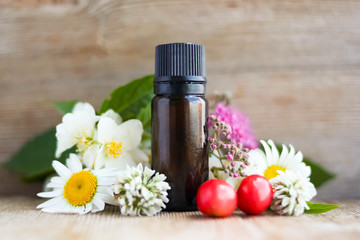 Spa perfume essential aroma oil glass bottle with flower blossoms on old wooden background