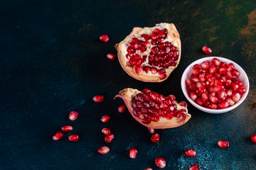 Red juice pomegranate on dark background. Ripe pomegranate with leaves on a dark background
