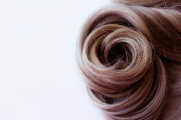 Naklejka premium Beautiful hair. Brown hair. Hair is gathered in a bun on a white background. With free space for text. For a poster or business card.