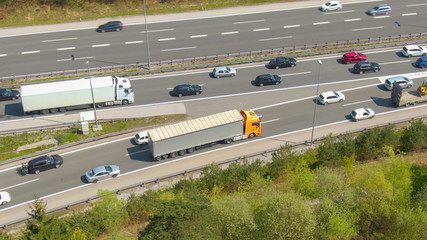 DRONE: Big orange 18 wheeler follows the congested traffic along the entry lane.