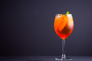 Cocktail aperol spritz on black background. Summer alcohol cocktail with orange fruit and fresh mint. Italian cocktail aperol spritz on wooden boards