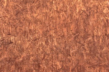 The structure of the wood chipboard, painted in red-brown color close-up. Abstract background