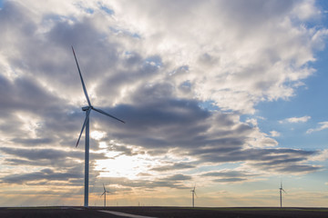Wind turbines on agricultural ground with cloudy sky in background