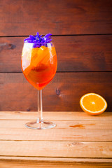 Aperol spritz cocktail on wooden boards. Summer alcoholic cocktail with orange slices and flowers. Aperol spritz on wooden boards
