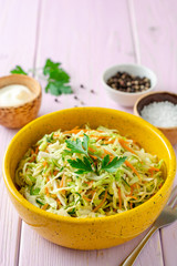 Coleslaw salad with cabbage, carrot and cucumber in bowl on purple wooden background. Selective focus.