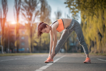 attractive brunette woman warm up and stretching in park at sunshine