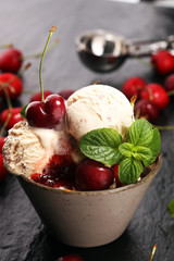 Cherry and vanilla ice cream scoop with fresh cherries and mint on a rustic background