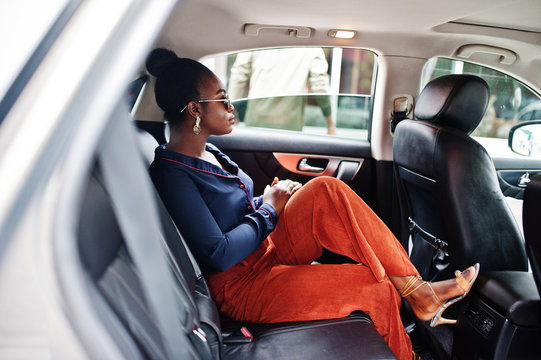 Rich business african woman on sunglasses sit at suv car with black leather seats.