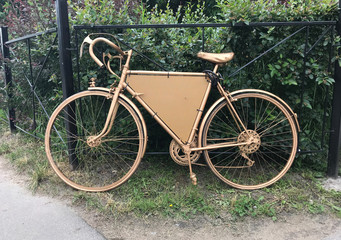 Fototapeta na wymiar Golden retro bike in front of bushes