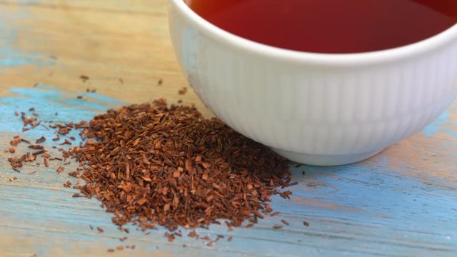 rooibos tea, made from the South African red bush, naturally caffeine free - a cup of tea and loose leaves on turntable