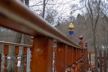 Wooden brown carved railing of the bridge leading to the Orthodox church