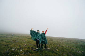 Happy female couple hikers posing in foggy mountains.