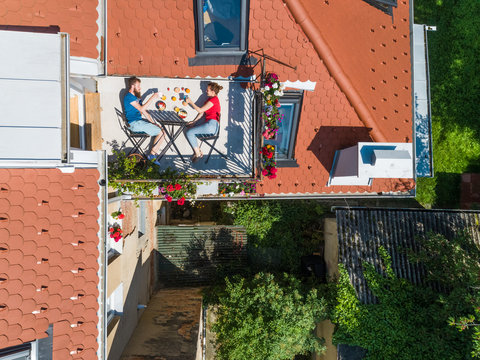 Aerial view of couple having breakfast on roof terrace. Fun concept for people living in the city. - Powered by Adobe
