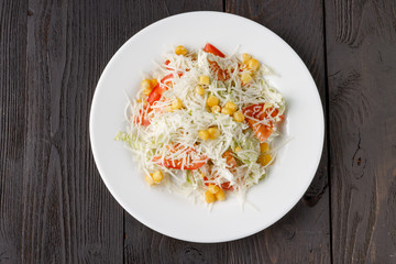 Fresh salad in wooden plate on wood table