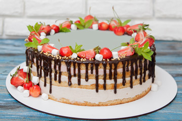 Cake with strawberries and cherries, decorated with mint and marshmallows, with chocolate drips