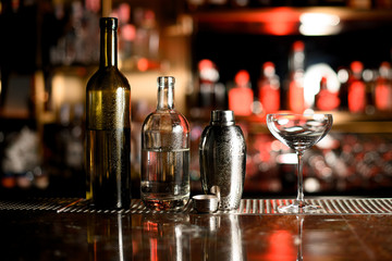 Two bottles, shaker and glass on bar counter