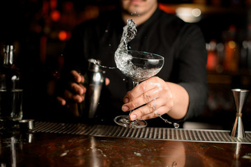 Bartender shakes alcohol in glass at counter