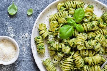 Pasta with pesto and parmesan on a concrete background. View from above.