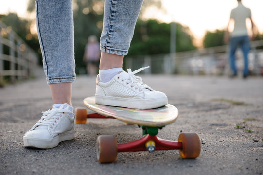 Girl with longboard wearing sneakers shoes in urban style