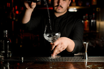 Bartender pouring alcohol from shaker to glass