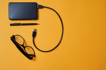Blogging, blog and blogger or social media concept: glasses and an external hard drive on a yellow background. Flat lay
