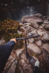 Tourist is taking a photo of river while driving scooter in the wild nature.