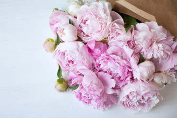 Bouquet of pink peonies in a paper bag on the table