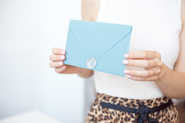 Close-up woman with slim body holding in hands the invitation card blue pink color square shape envelope card