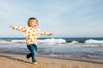 Happy little girl running barefoot on the beach