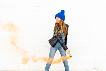 Smiling girl with orange smoke torch in front of white background