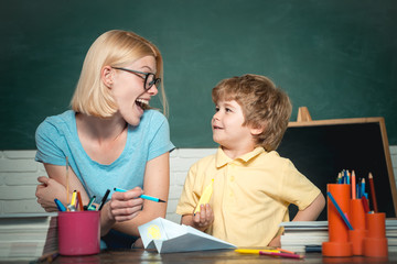 Back to school and happy time. Funny little child and young female teacher having fun on blackboard...