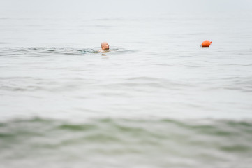 onely Head of a man swimming in sea to a buoy