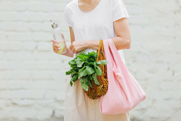 Female hands hold eco bag of vegetables, greens and reusable water bottle. Zero waste. Sustainable...
