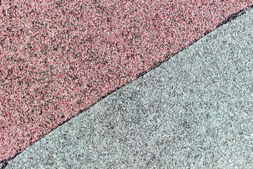 Roof covering of red and gray roofing material is divided by a black stripe along the diagonal. Ruberoid background.