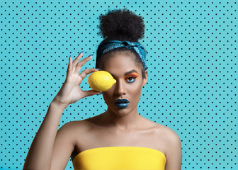 Beautiful attractive young woman with creative make-up and lemon near the eye