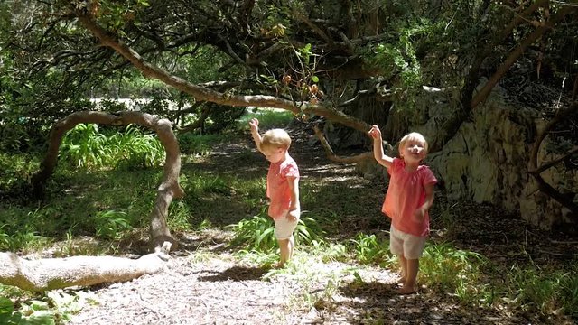 Twin Girls Enthralled By Butterfly Flying Around Them In A Milkwood Forest In Hermanus, South Africa