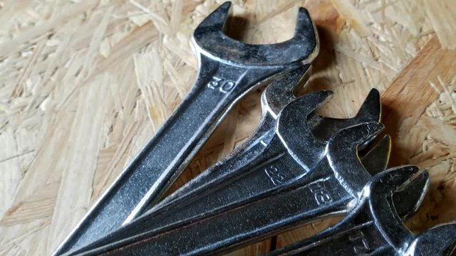 Retreating view showing wrenches on a plywood countertop in a pile