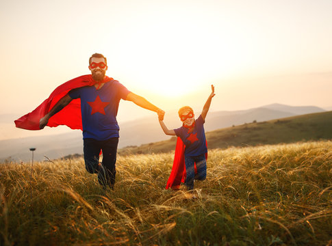 concept of father's day. dad and child daughter in hero superhero costume at sunset  .