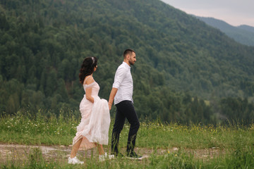 Fototapeta na wymiar Groom and bride walking hougt the Carpathian mountains