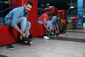 Happy family putting on roller skates indoors