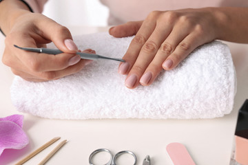 Obraz na płótnie Canvas Woman preparing fingernail cuticles at table, closeup. At-home manicure